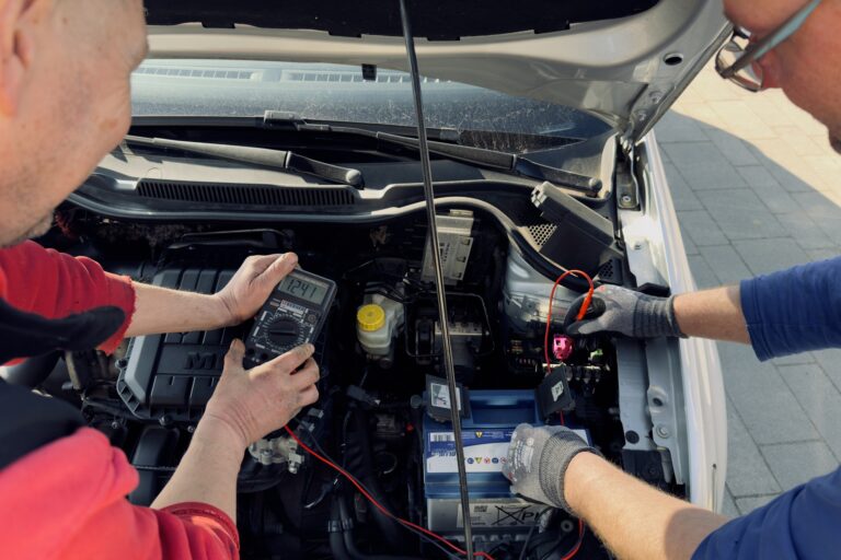Zwei Männer, die die Elektrik eines Kfz reparieren